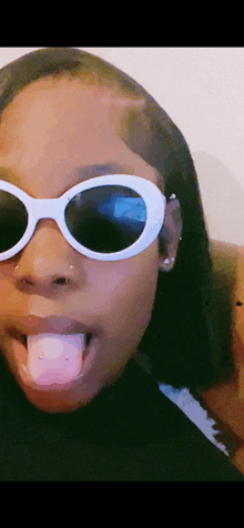 a woman wearing sunglasses sticks out her tongue