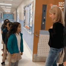 a girl in a blue jacket is talking to a teacher in a hallway with hap pily written in the corner