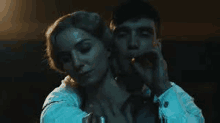 a man is smoking a cigarette while a woman is holding his neck .