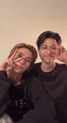 two young men are posing for a picture and one of them is wearing a black shirt that says ' x ' on it