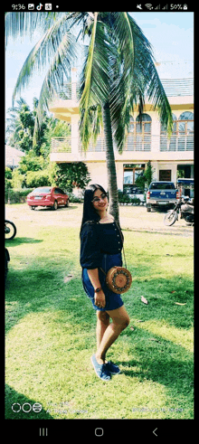 a woman standing in front of a palm tree with a phone screen showing the time as 9:36