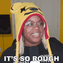 a woman wearing a yellow winnie the pooh hat and glasses says it 's so rough