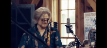 a man is playing a guitar in front of a microphone while wearing sunglasses and a wig .