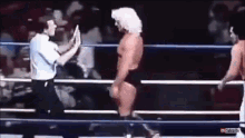 a referee is giving a high five to a wrestler in the ring .