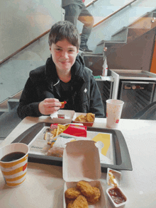 a young boy sits at a table with a mcdonald 's tray of food