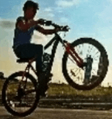 a man is riding a bike on a road and doing a trick .