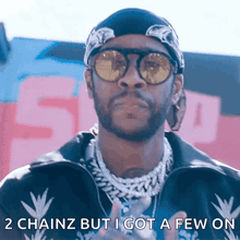 a man wearing sunglasses and a bandana has the words 2 chainz but i got a few on below him