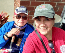 a man wearing a national guard hat is sitting next to a woman wearing a red shirt