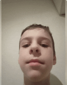 a young boy is taking a selfie with his mouth open and looking at the camera .