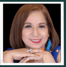 a woman wearing a ring and earrings is smiling with her hands folded .