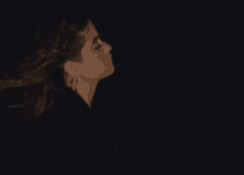 a woman with her hair blowing in the wind in the dark