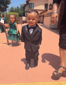 a little boy in a tuxedo stands next to two little girls