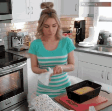 a woman in a blue and white striped shirt is preparing food in a kitchen with a sign that says alicity