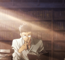 a man in glasses is reading a book in front of a bookshelf