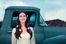 a woman in a white dress is standing in front of a pickup truck