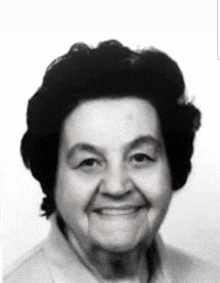 a black and white photo of an older woman smiling for the camera .