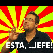 a man with glasses and a beard says " esta jefe " in front of a colorful background