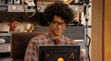 a man sitting in front of a computer with a sign that says no smoking on the shelf behind him