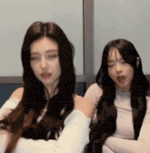 two women with long hair are sitting next to each other and one of them is making a funny face .