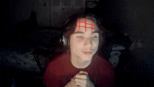 a person with a red cross on their forehead is wearing headphones