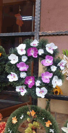 a wreath with pink and white flowers is hanging on a window