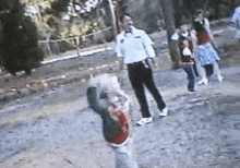 a man in a police uniform is standing next to a child in a red shirt .