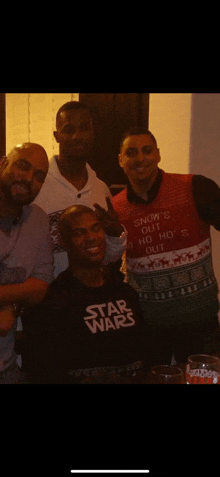 a man wearing a star wars t-shirt poses with two other men