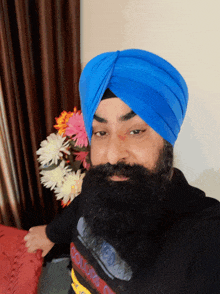 a man with a beard wearing a blue turban and a black shirt that says ' adidas ' on it