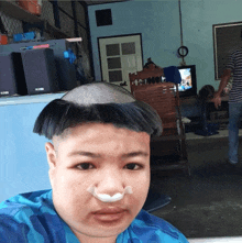 a man with a shaved head has a sticker on his nose that says ' a ' on it