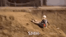 a man is doing a handstand on top of a sandy hill with the words `` smh '' written on the bottom .