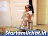 a little girl is riding a rocking horse and the website starttamilchat.in is displayed