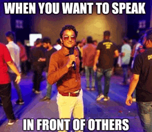 a man holding a microphone in front of a crowd with a caption that says when you want to speak in front of others