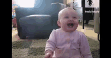 a baby is sitting on the floor in a living room with a chair and ottoman in the background .