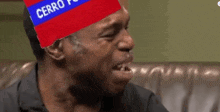 a man is sitting on a couch with a cerro flag on his head .