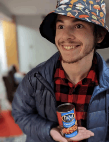 a man wearing a hat is holding a can of b&m beans