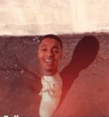 a man in a white shirt with the letter s on it is smiling