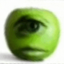 a green apple with a sad smiley face on it .