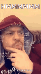a man in a hoodie is holding his hand to his chin while looking at a calculator .
