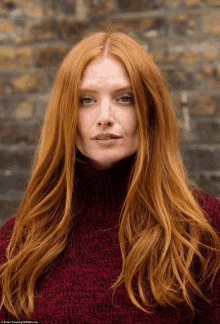 a woman with long red hair is wearing a sweater