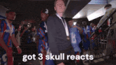 a man with a medal around his neck says " got 3 skull reacts " in front of a group of people
