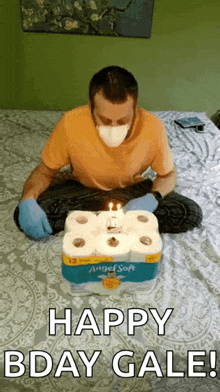 a man wearing a mask and gloves is sitting on a bed with a birthday cake made out of toilet paper .