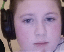 a boy wearing headphones looks at the camera with a serious look on his face