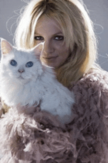 a woman is holding a white cat with blue eyes in her arms