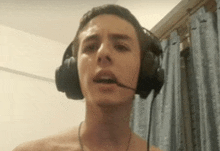 a shirtless man is wearing headphones with a microphone .