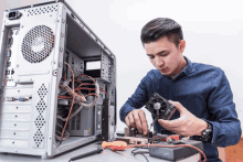 a man working on a computer with a fan and a screwdriver