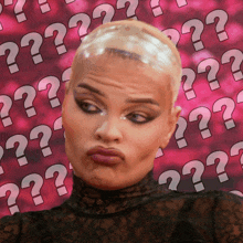 a woman is making a funny face in front of a pink background with question marks