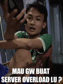 a man in a green shirt is sitting in a chair with the words mau gw buat server overload lu on the bottom