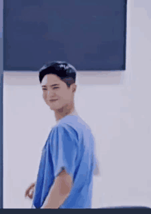 a young man in a blue scrub top is standing in a room .