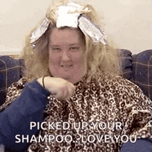 a woman with a wig on her head is sitting on a couch and says `` picked up your shampoo love you '' .