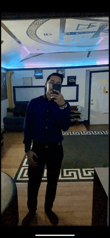 a man taking a selfie in front of a mirror with a greek key rug